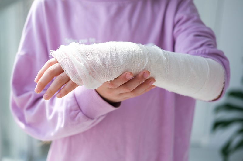Close-up of a broken arm of a child in a cast. The girl holds her hand folded against. A child with a plaster on his hand