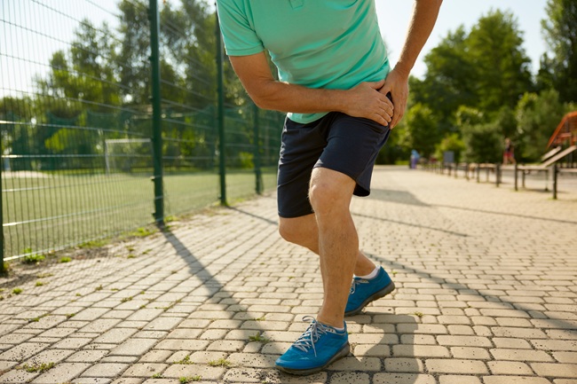 Senior sportsman suffering with hip having injury during jogging workout. 