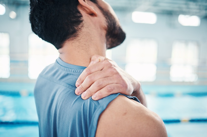 A man rubbing his shoulder in pain, stiffness, and discomfort.